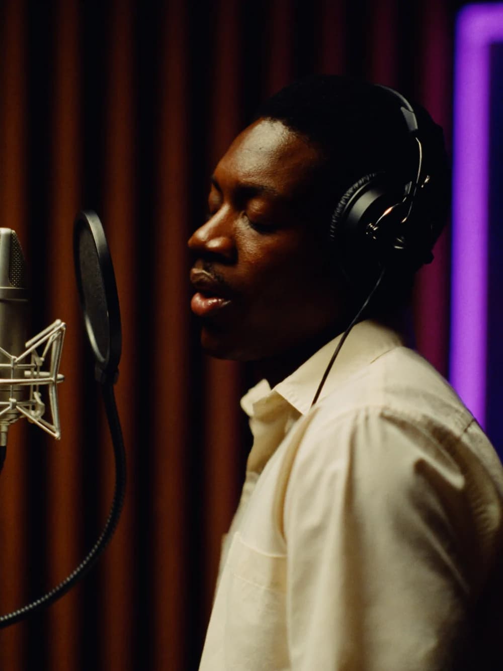 Illustrative singer recording in an amber-lit studio